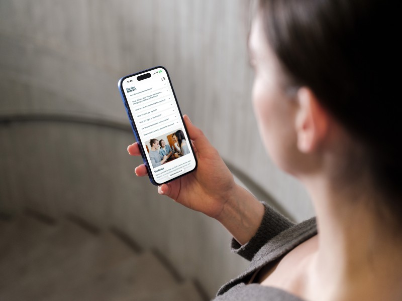 mockuuups iphone 16 mockup held in a womans hand against concrete background