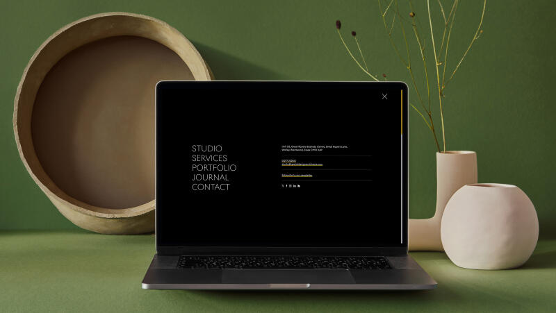 mockuuups macbook mockup on a green slab with flower vase at the side